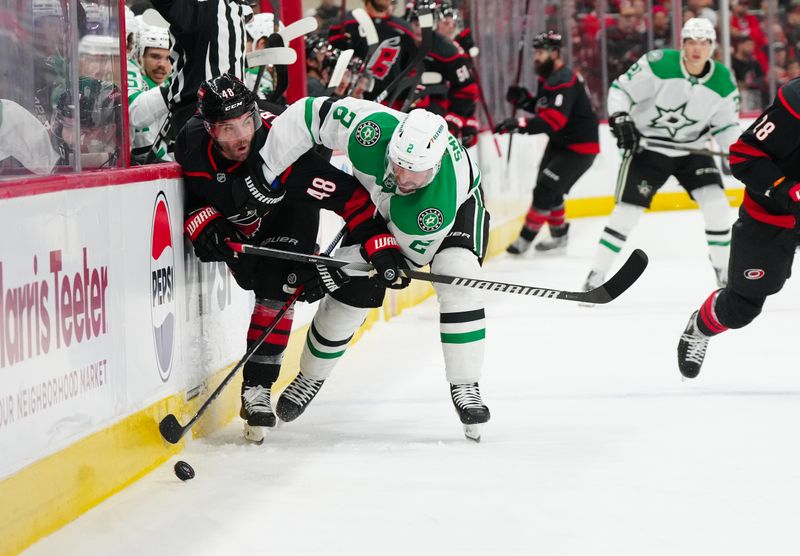 Nov 25, 2024; Raleigh, North Carolina, USA;  Dallas Stars defenseman Brendan Smith (2) and Carolina Hurricanes left wing Jordan Martinook (48) battle over the puck during the first period at Lenovo Center. Mandatory Credit: James Guillory-Imagn Images