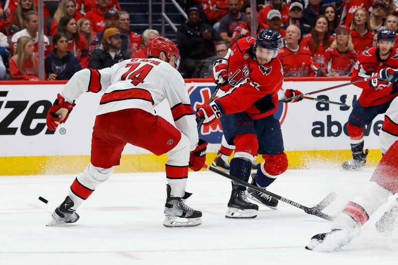 May 8, 2025; Washington, District of Columbia, USA; Washington Capitals right wing Brandon Duhaime (22) shoots the puck as Carolina Hurricanes defenseman Jaccob Slavin (74) defends in the third period in game two of the second round of the 2025 Stanley Cup Playoffs at Capital One Arena. Mandatory Credit: Geoff Burke-Imagn Images