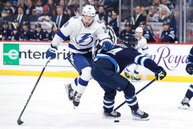 Jan 2, 2024; Winnipeg, Manitoba, CAN; Tampa Bay Lightning left wing Brandon Hagel (38) leaps over Winnipeg Jets defenseman Josh Morrissey (44) to regain puck control in the first period at Canada Life Centre. Mandatory Credit: James Carey Lauder-USA TODAY Sports