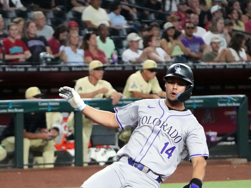 Aug 13, 2024; Phoenix, Arizona, USA; Colorado Rockies shortstop Ezequiel Tovar (14) slides and scores a run against the Arizona Diamondbacks during the third inning at Chase Field. Mandatory Credit: Joe Camporeale-USA TODAY Sports