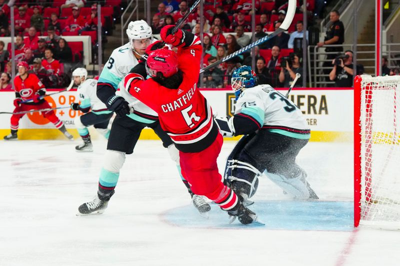 Oct 26, 2023; Raleigh, North Carolina, USA; Seattle Kraken defenseman Brian Dumoulin (8) checks Carolina Hurricanes defenseman Jalen Chatfield (5) during the third period at PNC Arena. Mandatory Credit: James Guillory-USA TODAY Sports