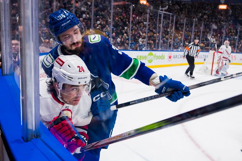 Dec 9, 2023; Vancouver, British Columbia, CAN; Vancouver Canucks forward Phillip Di Giuseppe (34) checks Carolina Hurricanes forward Seth Jarvis (24) in the first period at Rogers Arena. Mandatory Credit: Bob Frid-USA TODAY Sports