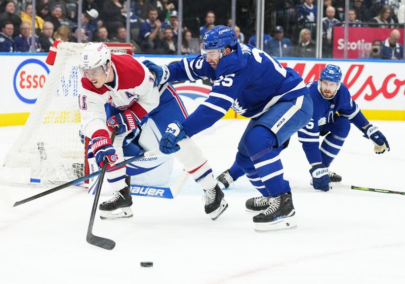 Nov 9, 2024; Toronto, Ontario, CAN; Montreal Canadiens right wing Brendan Gallagher (11) battles for the puck with Toronto Maple Leafs defenseman Conor Timmins (25) during the second period at Scotiabank Arena. Mandatory Credit: Nick Turchiaro-Imagn Images