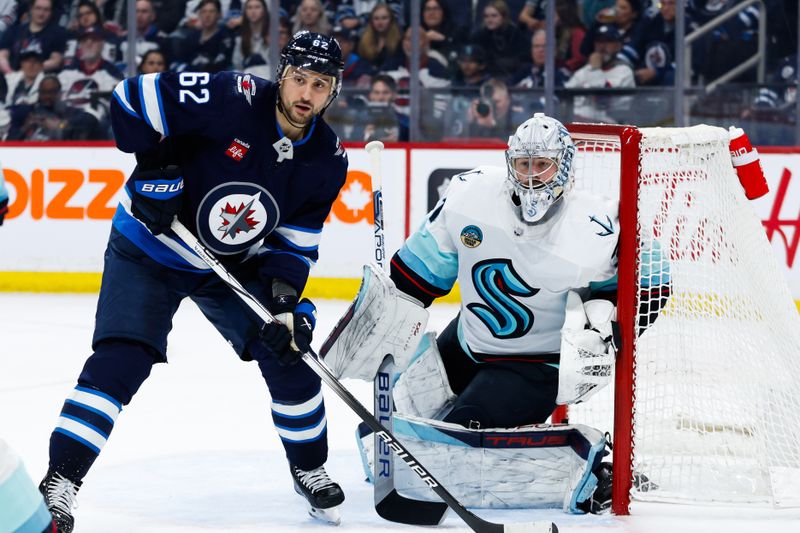 Apr 16, 2024; Winnipeg, Manitoba, CAN;  Seattle Kraken goalie Philipp Grubauer (31) and Winnipeg Jets forward Nino Niederreiter (62) look for the puck during the second period at Canada Life Centre. Mandatory Credit: Terrence Lee-USA TODAY Sports