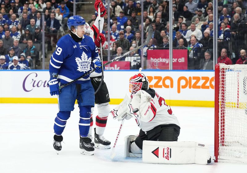 Mar 26, 2024; Toronto, Ontario, CAN; Toronto Maple Leafs left wing Tyler Bertuzzi (59) battles for the puck with New Jersey Devils defenseman Nick DeSimone (57) in front of  goaltender Jake Allen (34) during the first period at Scotiabank Arena. Mandatory Credit: Nick Turchiaro-USA TODAY Sports