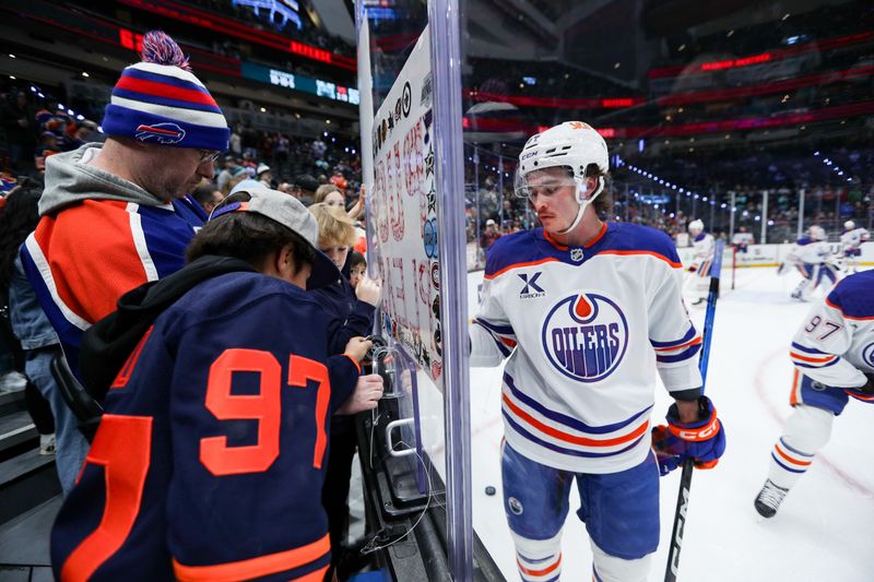 Nov 29, 2025; Seattle, Washington, USA; Edmonton Oilers center Connor Clattenburg (64) gives a fan a puck before the game against the Seattle Kraken at Climate Pledge Arena. Mandatory Credit: Kevin Ng-Imagn Images