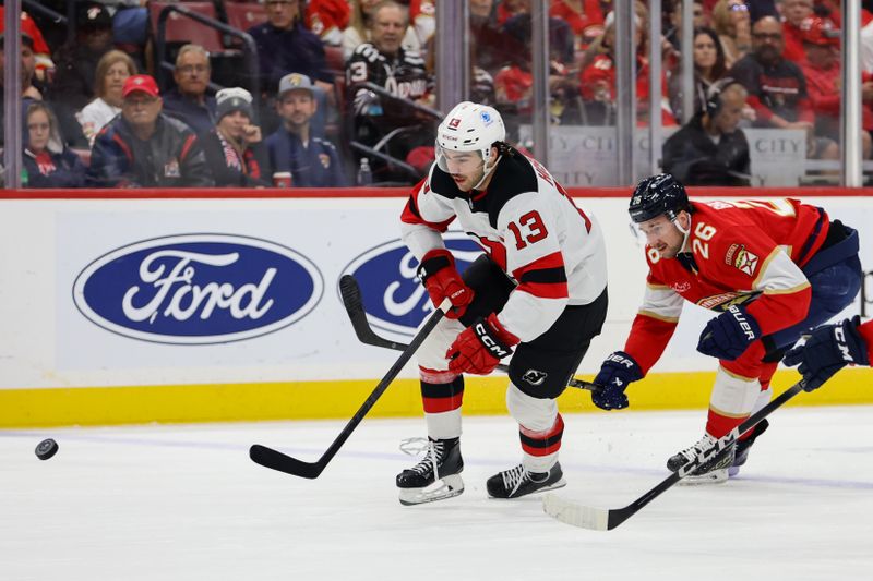 Nov 12, 2024; Sunrise, Florida, USA; New Jersey Devils center Nico Hischier (13) moves the puck past Florida Panthers defenseman Uvis Balinskis (26) during the first period at Amerant Bank Arena. Mandatory Credit: Sam Navarro-Imagn Images