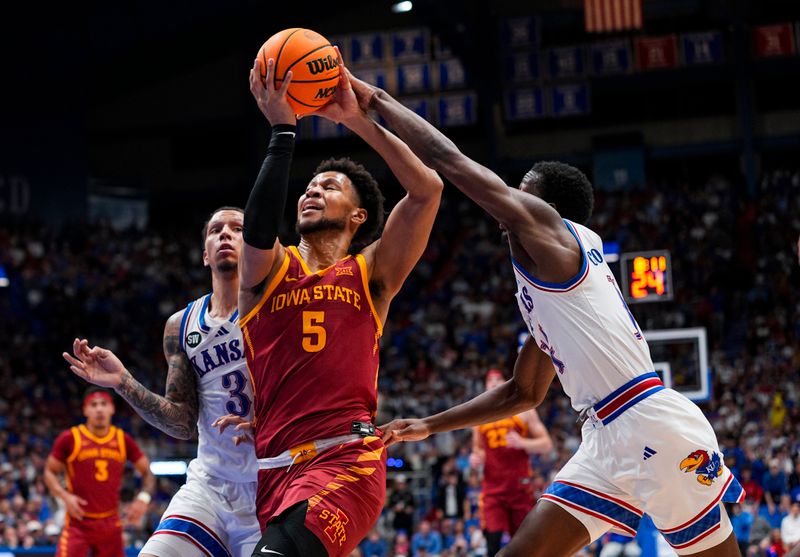 Jan 13, 2026; Lawrence, Kansas, USA; Iowa State Cyclones forward Joshua Jefferson (5) drives against Kansas Jayhawks guard Tre White (3) and guard Melvin Council Jr. (14) during the first half at Allen Fieldhouse. Mandatory Credit: Jay Biggerstaff-Imagn Images