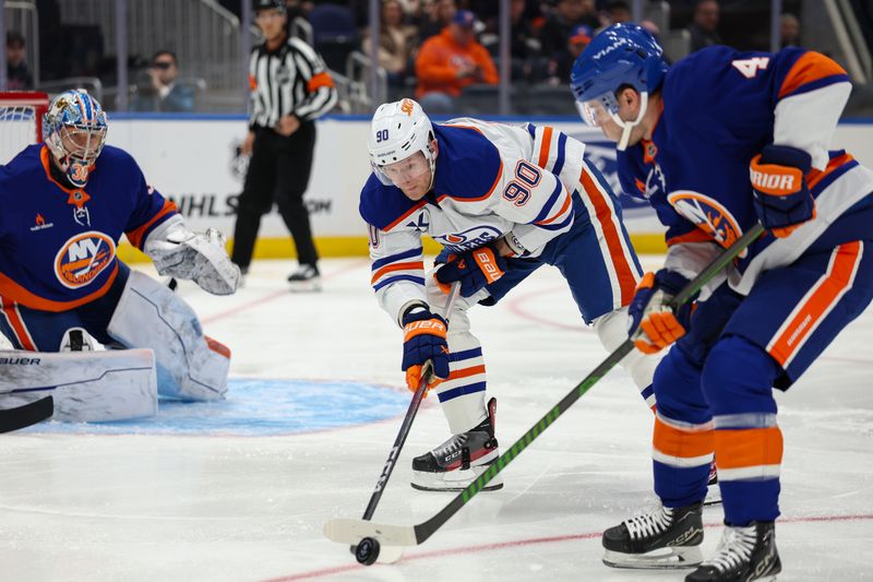 Mar 14, 2025; Elmont, New York, USA; Edmonton Oilers right wing Corey Perry (90) reaches for the puck against the New York Islanders during the first period at UBS Arena. Mandatory Credit: Thomas Salus-Imagn Images