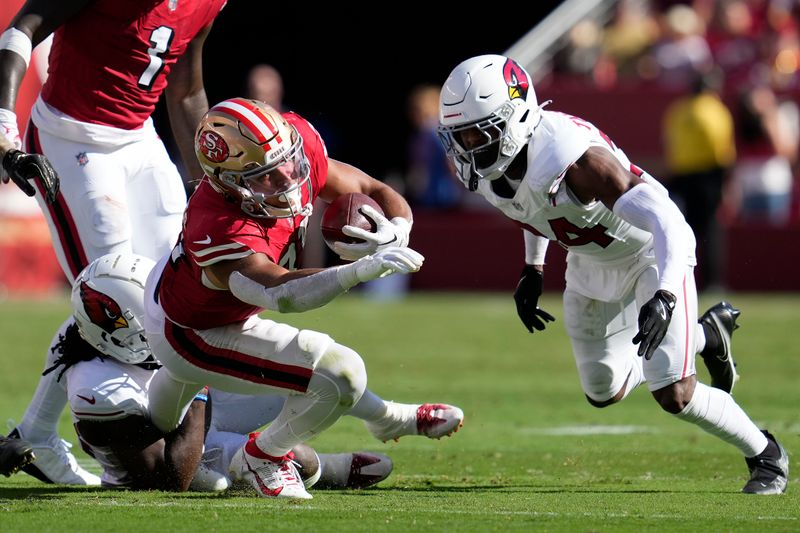 San Francisco 49ers running back Isaac Guerendo, middle, runs against Arizona Cardinals cornerback Starling Thomas V, left, and safety Jalen Thompson during the second half of an NFL football game in Santa Clara, Calif., Sunday, Oct. 6, 2024. (AP Photo/Godofredo A. Vásquez)