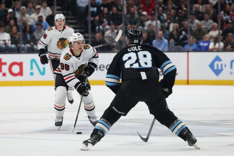 Feb 25, 2025; Salt Lake City, Utah, USA; Chicago Blackhawks center Connor Bedard (98) skates with the puck against Utah Hockey Club defenseman Ian Cole (28) during the second period at Delta Center. Mandatory Credit: Rob Gray-Imagn Images