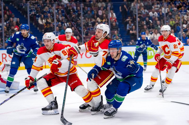 Nov 12, 2024; Vancouver, British Columbia, CAN; Calgary Flames defenseman Brayden Pachal (94) and forward Ryan Lomberg (70) battle with Vancouver Canucks defenseman Erik Brannstrom (26) during the second period at Rogers Arena. Mandatory Credit: Bob Frid-Imagn Images