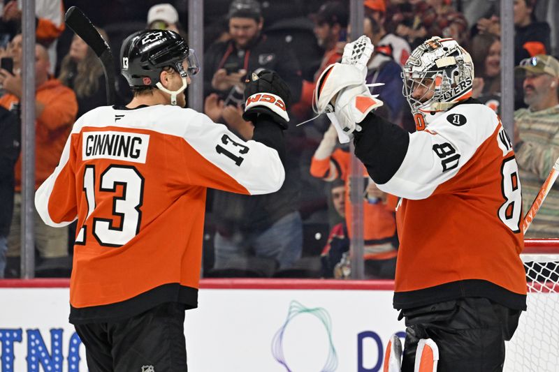 Oct 13, 2025; Philadelphia, Pennsylvania, USA; Philadelphia Flyers defenseman Adam Ginning (13) and goaltender Dan Vladar (80) celebrate win against the Florida Panthers at Wells Fargo Center. Mandatory Credit: Eric Hartline-Imagn Images