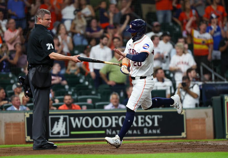 May 27, 2025; Houston, Texas, USA; Umpire Jordan Baker (71) hands Houston Astros left fielder Chas McCormick (20) the bat after he scored against the Athletics in the second inning at Daikin Park. Mandatory Credit: Thomas Shea-Imagn Images