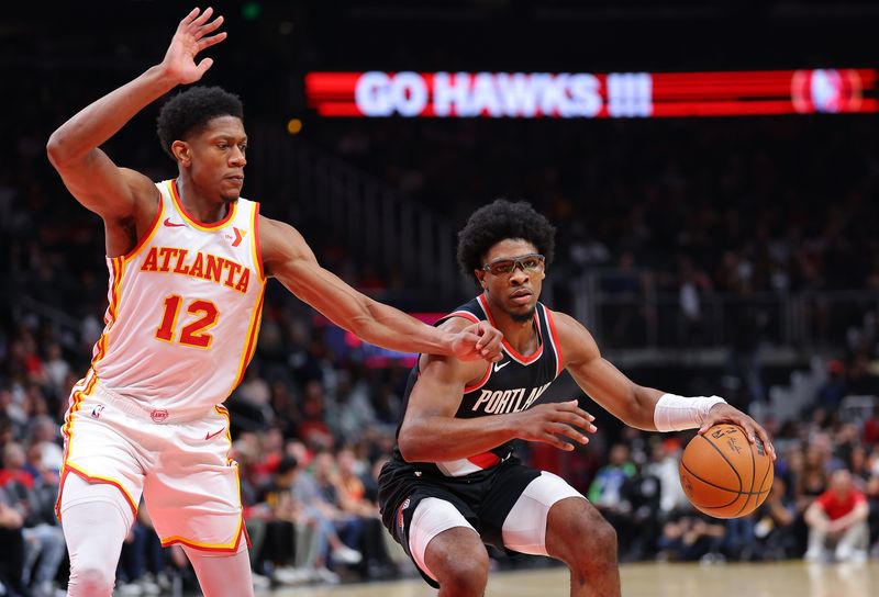 ATLANTA, GEORGIA - MARCH 27:  Scoot Henderson #00 of the Portland Trail Blazers drives against De'Andre Hunter #12 of the Atlanta Hawks during the second quarter at State Farm Arena on March 27, 2024 in Atlanta, Georgia.  NOTE TO USER: User expressly acknowledges and agrees that, by downloading and/or using this photograph, user is consenting to the terms and conditions of the Getty Images License Agreement.  (Photo by Kevin C. Cox/Getty Images)