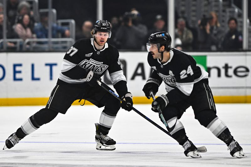 Mar 22, 2025; Los Angeles, California, USA; Los Angeles Kings left wing Warren Foegele (37) moves the puck with center Phillip Danault (24) against the Carolina Hurricanes during the second period at Crypto.com Arena. Mandatory Credit: Jonathan Hui-Imagn Images