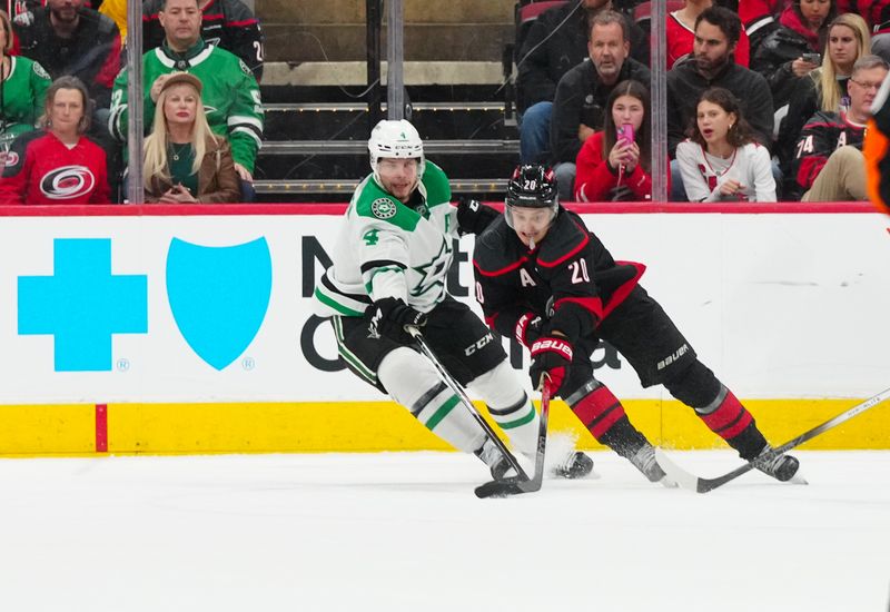 Nov 25, 2024; Raleigh, North Carolina, USA;  Carolina Hurricanes center Sebastian Aho (20) skates with the puck outside Dallas Stars defenseman Miro Heiskanen (4) during the second period at Lenovo Center. Mandatory Credit: James Guillory-Imagn Images