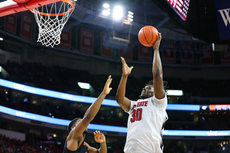 Jan 14, 2023; Raleigh, North Carolina, USA; North Carolina State Wolfpack forward D.J. Burns Jr. (30) shoots the ball while being defended by Miami Hurricanes forward Norchad Omier (15) during the first half at PNC Arena. Mandatory Credit: Jaylynn Nash-USA TODAY Sports 