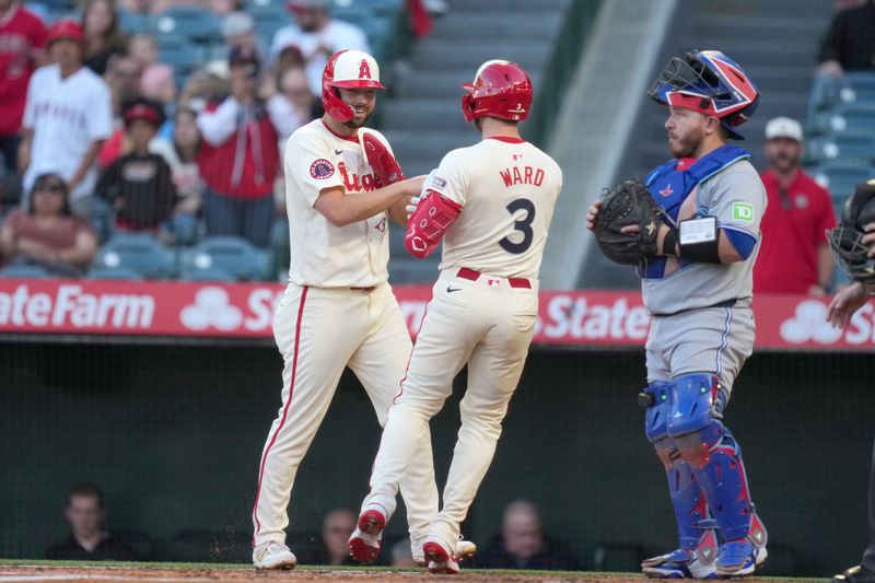 May 8, 2025; Anaheim, California, USA; Los Angeles Angels left fielder Taylor Ward (3) celebrates with first baseman Nolan Schanuel (18) after hitting a two-run home run in the first inning as Toronto Blue Jays catcher Alejandro Kirk (30) watches at Angel Stadium. Mandatory Credit: Kirby Lee-Imagn Images