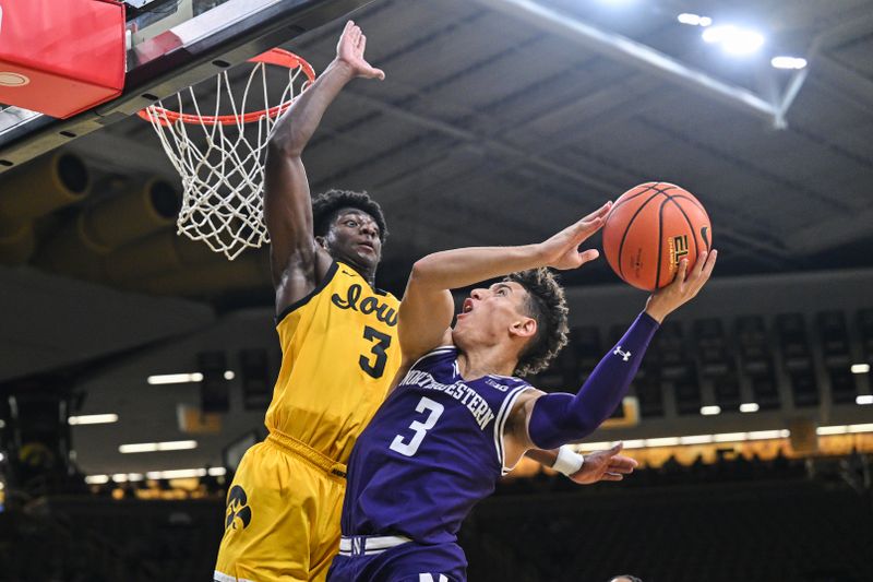 Dec 3, 2024; Iowa City, Iowa, USA; Northwestern Wildcats guard Ty Berry (3) shoots against Iowa Hawkeyes guard Drew Thelwell (3) during the first half at Carver-Hawkeye Arena. Mandatory Credit: Jeffrey Becker-Imagn Images