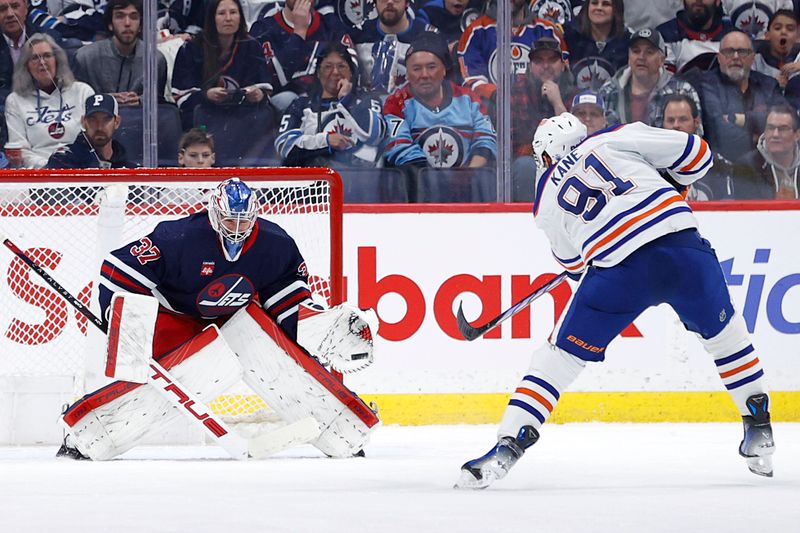 Mar 26, 2024; Winnipeg, Manitoba, CAN; Winnipeg Jets goaltender Connor Hellebuyck (37) makes glove save on Edmonton Oilers left wing Evander Kane (91) in the second period at Canada Life Centre. Mandatory Credit: James Carey Lauder-USA TODAY Sports