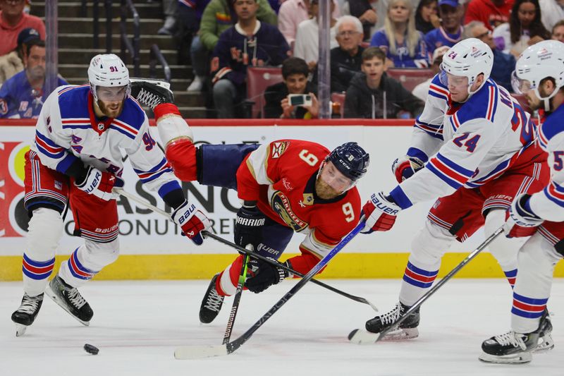 May 28, 2024; Sunrise, Florida, USA; Florida Panthers center Sam Bennett (9) attempts to move the puck between New York Rangers center Alex Wennberg (91) and right wing Kaapo Kakko (24) during the second period in game four of the Eastern Conference Final of the 2024 Stanley Cup Playoffs at Amerant Bank Arena. Mandatory Credit: Sam Navarro-USA TODAY Sports