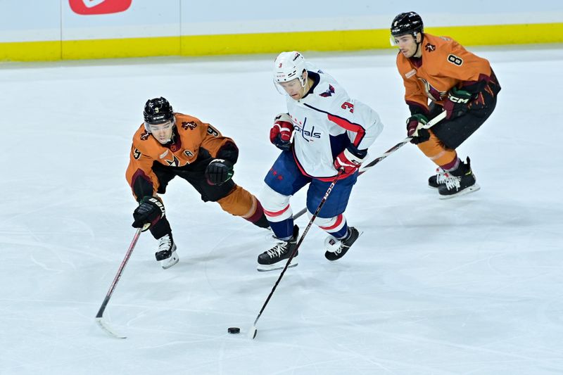 Jan 19, 2023; Tempe, Arizona, USA; Washington Capitals defenseman Nick Jensen (3) carries the puck as Arizona Coyotes center Nick Schmaltz (8) and right wing Clayton Keller (9) defend in the third period at Mullett Arena. Mandatory Credit: Matt Kartozian-USA TODAY Sports