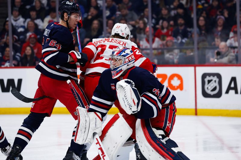 Jan 24, 2026; Winnipeg, Manitoba, CAN; Winnipeg Jets defenseman Logan Stanley (64) bodies Detroit Red Wings forward Michael Rasmussen (27) in front of goalie Connor Hellebuyck (37) during the first period at Canada Life Centre. Mandatory Credit: Terrence Lee-Imagn Images