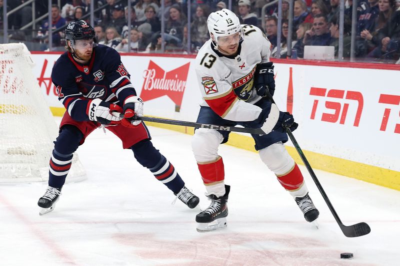 Jan 22, 2026; Winnipeg, Manitoba, CAN; Winnipeg Jets left wing Kyle Connor (81) defends Florida Panthers center Sam Reinhart (13) in the second period at Canada Life Centre. Mandatory Credit: James Carey Lauder-Imagn Images