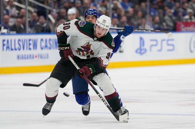 Feb 29, 2024; Toronto, Ontario, CAN; Arizona Coyotes defenseman J.J. Moser (90) tries to get control of the puck against the Toronto Maple Leafs during the third period at Scotiabank Arena. Mandatory Credit: John E. Sokolowski-USA TODAY Sports