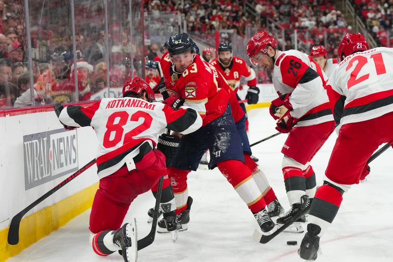 Dec 23, 2025; Raleigh, North Carolina, USA;  Florida Panthers left wing Brad Marchand (63) battles for the puck against Carolina Hurricanes center Jesperi Kotkaniemi (82) and defenseman Sean Walker (26) during the second period at Lenovo Center. Mandatory Credit: James Guillory-Imagn Images