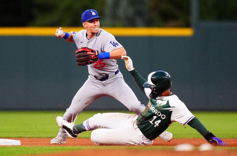 Sep 28, 2024; Denver, Colorado, USA; Los Angeles Dodgers shortstop Tommy Edman (25) turns a double play over Colorado Rockies shortstop Ezequiel Tovar (14) in the first inning at Coors Field. Mandatory Credit: Ron Chenoy-Imagn Images