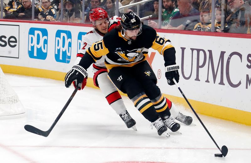 Oct 18, 2024; Pittsburgh, Pennsylvania, USA;  Pittsburgh Penguins defenseman Erik Karlsson (65) moves the puck against pressure from Carolina Hurricanes center Jesperi Kotkaniemi (82) during the second period at PPG Paints Arena. Mandatory Credit: Charles LeClaire-Imagn Images