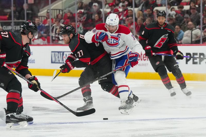 Jan 1, 2026; Raleigh, North Carolina, USA;  Montréal Canadiens center Nick Suzuki (14) checks Carolina Hurricanes left wing Nikolaj Ehlers (27) during the first period at Lenovo Center. Mandatory Credit: James Guillory-Imagn Images
