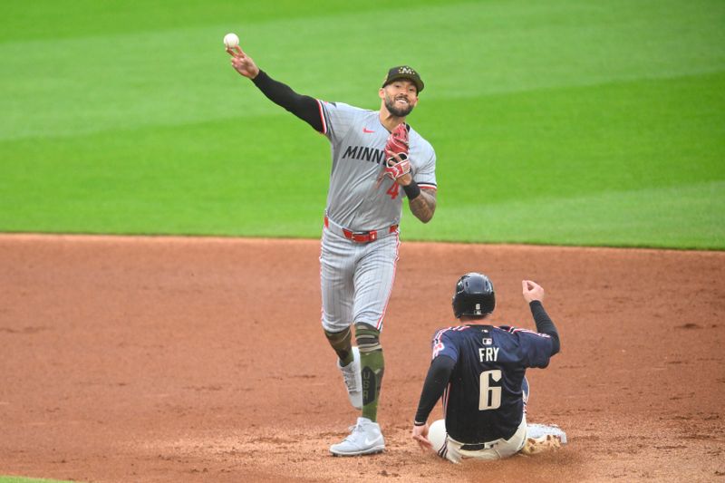 May 17, 2024; Cleveland, Ohio, USA; Minnesota Twins shortstop Carlos Correa (4) throws to first base beside Cleveland Guardians designated hitter David Fry (6) on a fielder’s choice in the second inning at Progressive Field. Mandatory Credit: David Richard-USA TODAY Sports