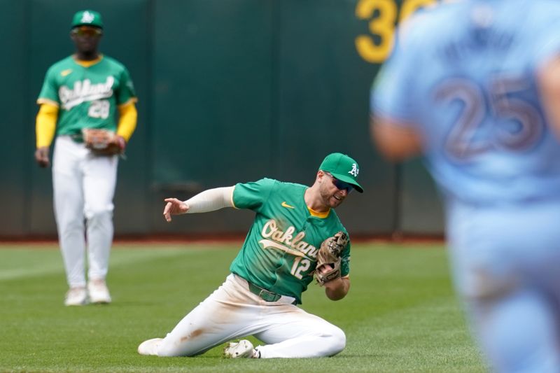 Jun 8, 2024; Oakland, California, USA; Oakland Athletics shortstop Max Schuemann (12) falls to the ground after catching a fly ball against the Toronto Blue Jays in the fourth inning at Oakland-Alameda County Coliseum. Mandatory Credit: Cary Edmondson-USA TODAY Sports