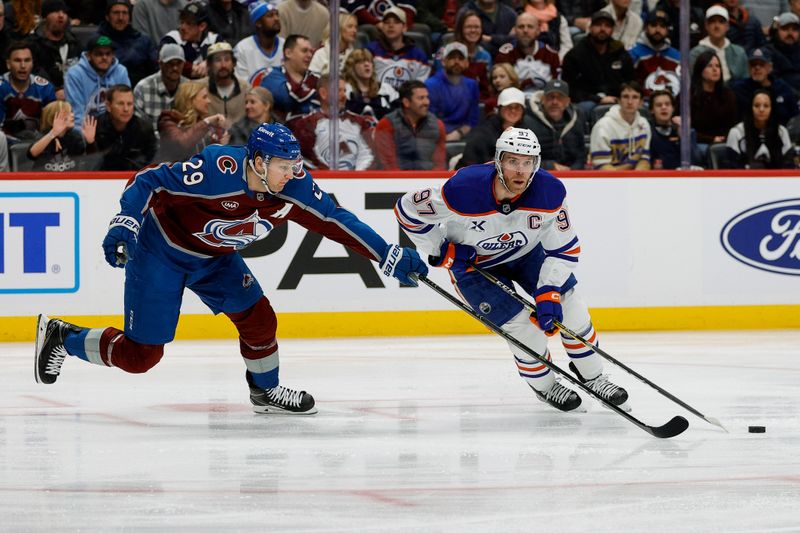 Jan 16, 2025; Denver, Colorado, USA; Colorado Avalanche center Nathan MacKinnon (29) knocks the puck away from Edmonton Oilers center Connor McDavid (97) in the first period at Ball Arena. Mandatory Credit: Isaiah J. Downing-Imagn Images