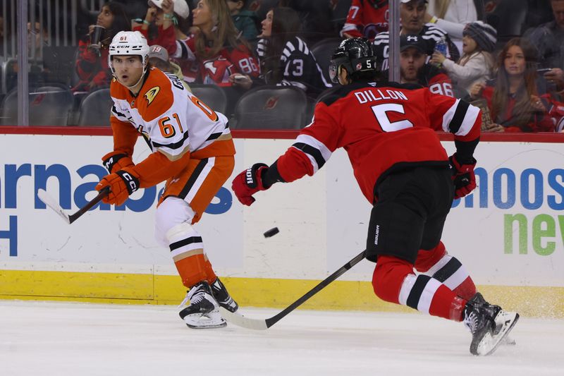 Oct 27, 2024; Newark, New Jersey, USA; Anaheim Ducks left wing Cutter Gauthier (61) passes the puck while being defended by New Jersey Devils defenseman Brenden Dillon (5) during the first period at Prudential Center. Mandatory Credit: Ed Mulholland-Imagn Images