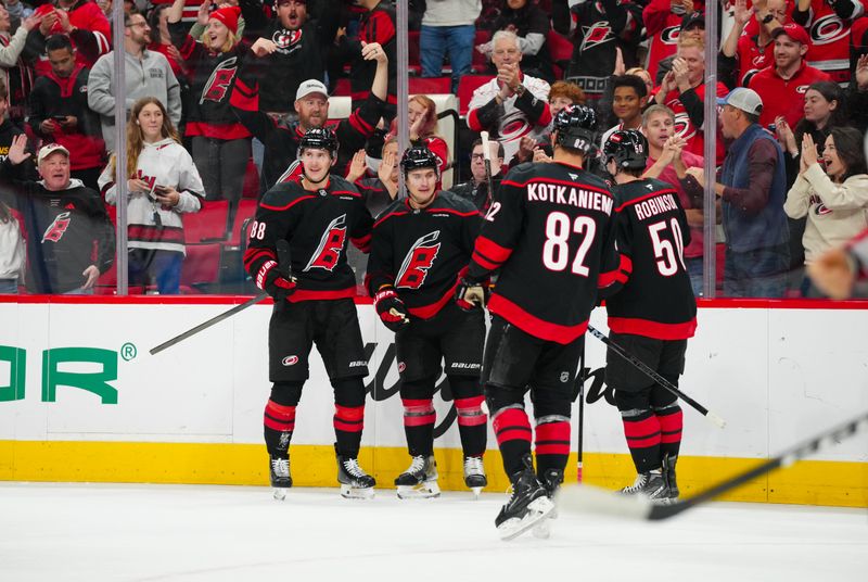 Nov 3, 2024; Raleigh, North Carolina, USA;  Carolina Hurricanes defenseman Dmitry Orlov (7) celebrates his goal with center Martin Necas (88) left wing Eric Robinson (50) and center Jesperi Kotkaniemi (82) against the Washington Capitals during the first period at Lenovo Center. Mandatory Credit: James Guillory-Imagn Images