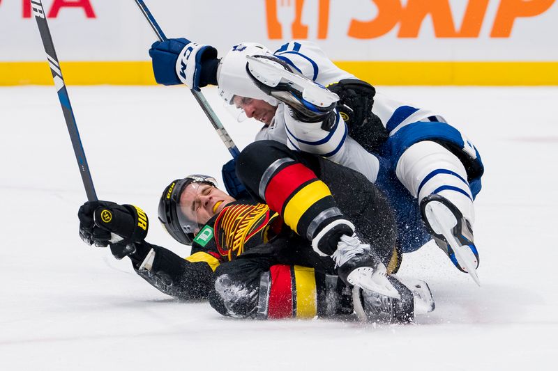 Jan 20, 2024; Vancouver, British Columbia, CAN; Toronto Maple Leafs forward John Tavares (91) checks Vancouver Canucks forward Teddy Blueger (53) in the first period at Rogers Arena. Mandatory Credit: Bob Frid-USA TODAY Sports