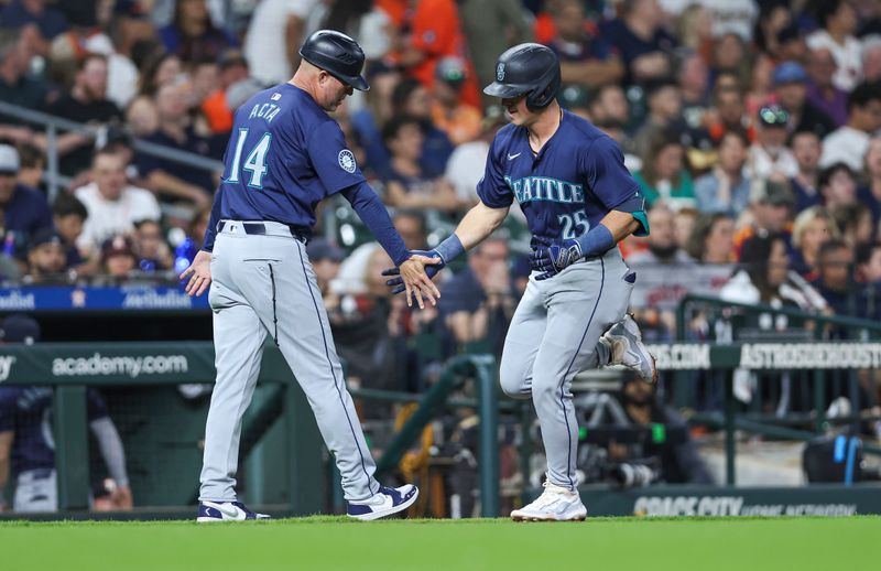 May 3, 2024; Houston, Texas, USA; Seattle Mariners shortstop Dylan Moore (25) celebrates with third base coach Manny Acta (14) after hitting a home run during the fifth inning against the Houston Astros at Minute Maid Park. Mandatory Credit: Troy Taormina-USA TODAY Sports