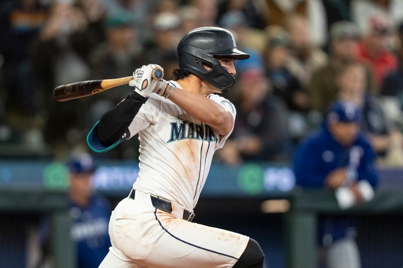 Jun 15, 2024; Seattle, Washington, USA;  Seattle Mariners third baseman Josh Rojas (4) hits a two-run single during the eighth inning against the Texas Rangers at T-Mobile Park. Mandatory Credit: Stephen Brashear-USA TODAY Sports