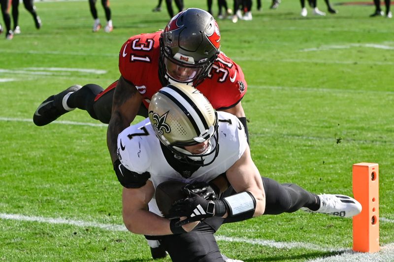 New Orleans Saints quarterback Taysom Hill (7) scores on a touchdown pass against Tampa Bay Buccaneers safety Antoine Winfield Jr. (31) in the first half of an NFL football game in Tampa, Fla., Sunday, Dec. 31, 2023. (AP Photo/Jason Behnken)