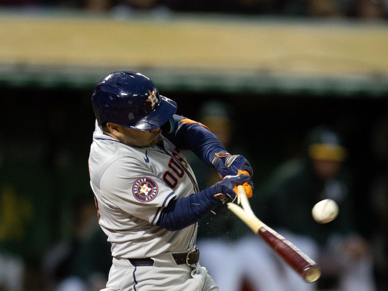 May 24, 2024; Oakland, California, USA; Houston Astros second baseman Jose Altuve (27) breaks his bat as he singles to center field against the Oakland Athletics during the sixth inning at Oakland-Alameda County Coliseum. Mandatory Credit: D. Ross Cameron-USA TODAY Sports