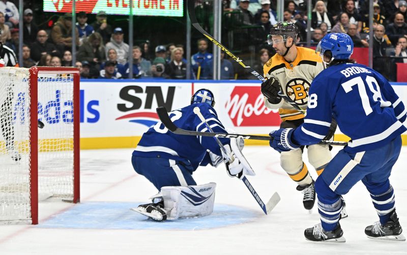 Dec 2, 2023; Toronto, Ontario, CAN; Boston Bruins forward Kevin Shattenkirk (12) scores a goal past Toronto Maple Leafs goalie Joseph Woll (60) in the second period at Scotiabank Arena. Mandatory Credit: Dan Hamilton-USA TODAY Sports