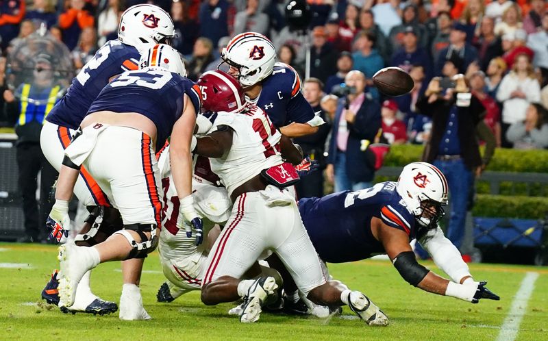 Nov 25, 2023; Auburn, Alabama, USA; Auburn Tigers quarterback Payton Thorne (1) fumbles the ball after being hit by Alabama Crimson Tide linebacker Chris Braswell (41) and linebacker Dallas Turner (15) during the fourth quarter at Jordan-Hare Stadium. Mandatory Credit: John David Mercer-USA TODAY Sports