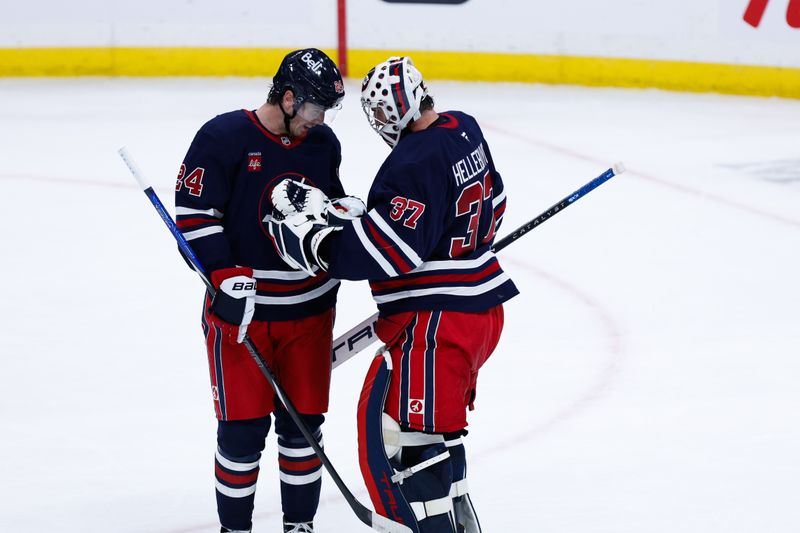 Oct 18, 2024; Winnipeg, Manitoba, CAN;  Winnipeg Jets goalie Connor Hellebuyck (37) is congratulated by Winnipeg Jets defenseman Hayden Fleury (24) on his win against the San Jose Sharks during the third period at Canada Life Centre. Mandatory Credit: Terrence Lee-Imagn Images