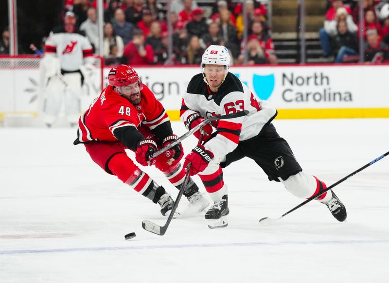 Oct 15, 2024; Raleigh, North Carolina, USA;  New Jersey Devils left wing Jesper Bratt (63) skates after the puck against Carolina Hurricanes left wing Jordan Martinook (48) during the second period at PNC Arena. Mandatory Credit: James Guillory-Imagn Images