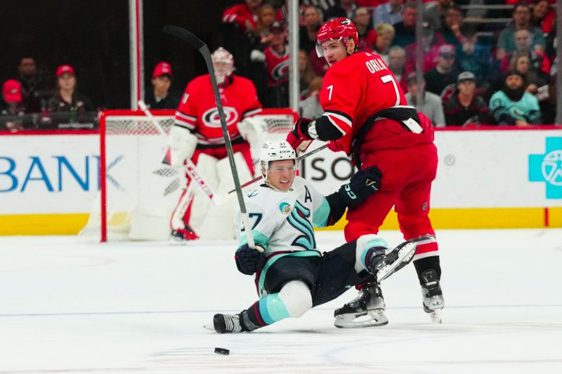 Oct 26, 2023; Raleigh, North Carolina, USA; Carolina Hurricanes defenseman Dmitry Orlov (7) checks Seattle Kraken center Yanni Gourde (37) during the first period at PNC Arena. Mandatory Credit: James Guillory-USA TODAY Sports