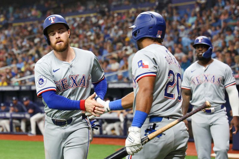 Apr 3, 2024; St. Petersburg, Florida, USA;  Texas Rangers first baseman Jared Walsh (21) is congratulated by third baseman Ezequiel Duran (20) after scoring a run against the Tampa Bay Rays in the ninth inning at Tropicana Field. Mandatory Credit: Nathan Ray Seebeck-USA TODAY Sports